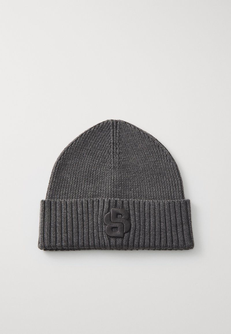 Dark gray knitted beanie with a ribbed cuff and a distinct black logo patch on the front, featuring a rounded shape and smooth texture.