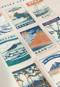 Kunsttryk med ni vintage rejseplakater, der viser landskaber, bjerge og vandlandskaber i forskellige farver og stilarter. Tekstetiketter inkluderet.