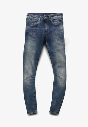 Jeans de mezclilla azul con un corte ajustado, que presentan un lavado deslavado, bolsillos estándar y costuras distintivas a lo largo de las piernas.