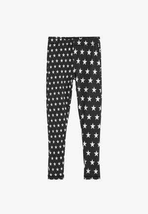 Mustat leggingsit valkoisilla tähtikuoseilla; vasemman jalan lahkeet pienemmillä tähdillä ja oikean jalan lahkeet isommilla tähdillä, molemmat kattavat koko kankaan.