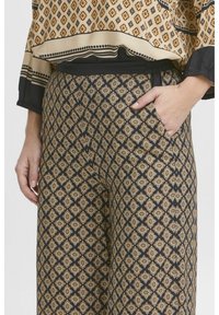 Pantalon noir à motifs avec des motifs de diamants dorés et beiges, doté d'une coupe décontractée, d'une taille élastique et de poches latérales.