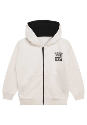 Kremfarvet lynlåshættejakke med sort foer i hætten, forlommer og Looney Tunes x DKNY-logo på venstre bryst.