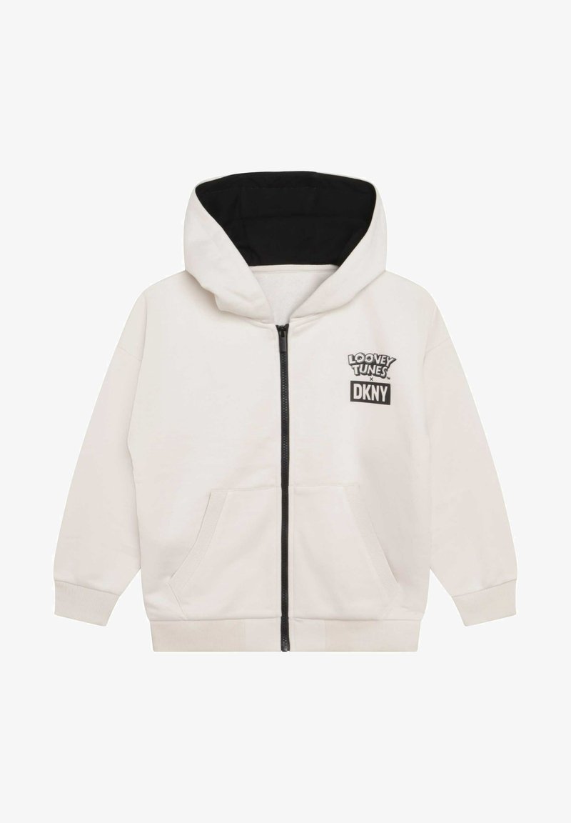 Sweat à capuche zippé couleur crème avec doublure intérieure de la capuche noire, poches avant, et logo Looney Tunes x DKNY sur la poitrine gauche.