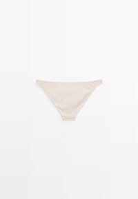 Beige thong brief with a smooth texture, elastic waistband, and minimal coverage design. Material appears soft and stretchy.