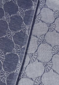 Textiel met een blauw en lichtblauw patroonontwerp met cirkelvormige motieven, verbonden door textuurlijnen, in een geweven stof.