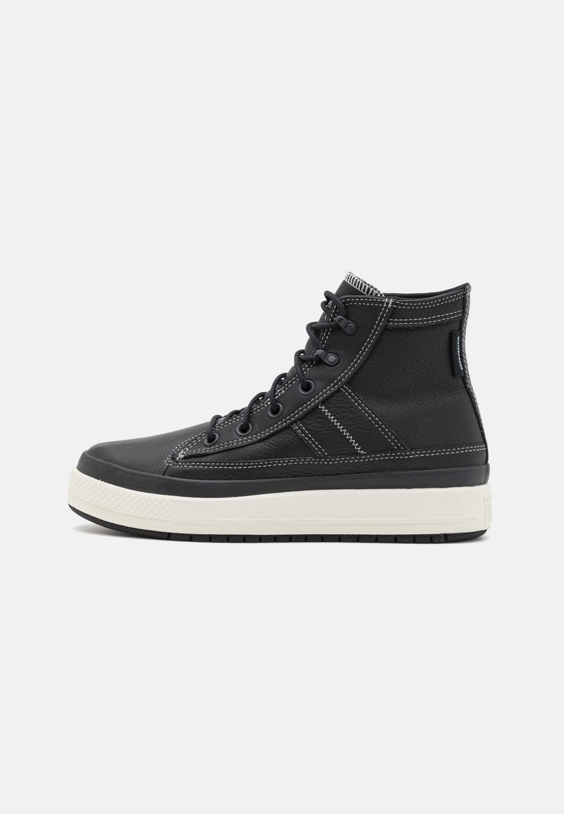 Black high-top sneakers made of textured leather, featuring white stitching, a white rubber sole, and black laces.