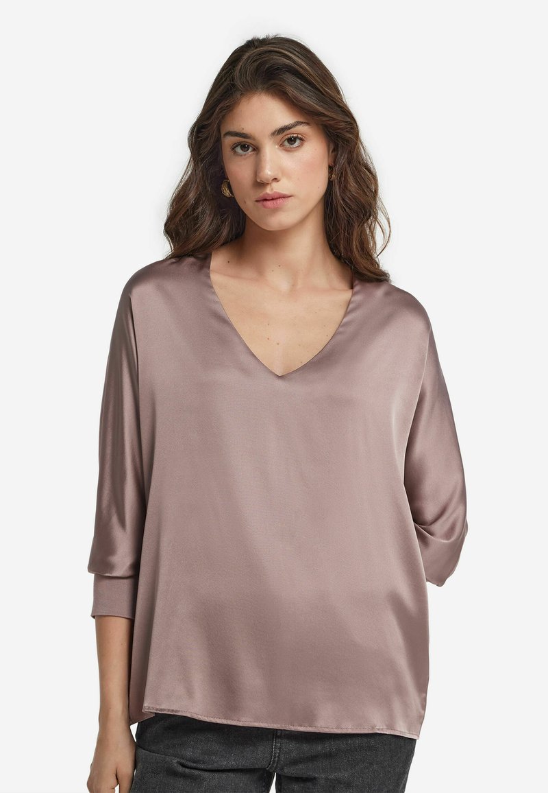 Satinbluse in Mauve, mit V-Ausschnitt, trois-quart-Ärmeln und lockerer Passform. Glatte Textur mit minimalen Nähten.