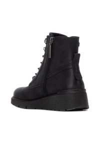 Botín negro de cuero a la altura del tobillo con cremallera lateral, cordones en la parte delantera, suela de goma texturizada y punta redondeada. Cuenta con un pequeño lazo en la parte trasera para facilitar el uso.