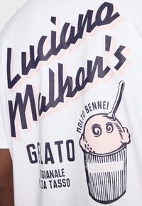 White cotton t-shirt with graphic print. Features bold text in navy and pink with a gelato illustration and accented detail.
