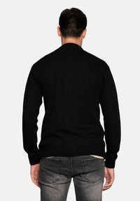 Black knitted sweater with a round neck and ribbed cuffs and hem, shown from the back on a model against a plain background.