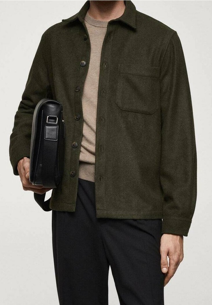 Mørkeolivengrøn skjortejakke i tekstureret uldblanding med en forlommer, knaplukning, båret over en beige crew neck, med en sort taske.