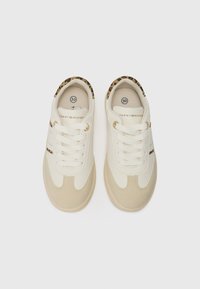 Vita och beige sneakers med en slät yta, snörningsdesign och leopardtryckselement längs kragen. Guldbranding på sidan.