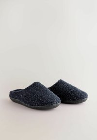 Dark blue, fuzzy slippers with a textured upper, closed-back design, and a sturdy black rubber sole. Soft material for comfort.