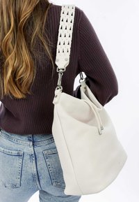 Borsa in pelle bianca con una superficie testurizzata, caratterizzata da una tracolla intrecciata e hardware in metallo argentato. La borsa ha una forma morbida ed è dotata di una chiusura a zip.