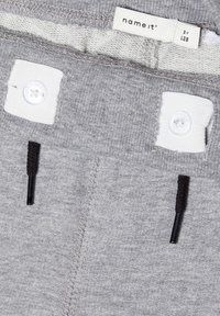 Graue Baumwollshorts mit weißem Knopfverschluss und verstellbarem schwarzen Kordelzug. Auffälliger Strukturstoff mit verstärkten Nähten. Markenlabel sichtbar.
