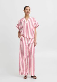 Striped linen two-piece outfit featuring short-sleeved top and wide-leg pants in pink, white, and gray tones, with a relaxed fit.