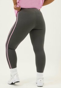 Grå leggings med rosa sidremsor, åtsittande design, mjuk textur, kombinerade med vita sneakers och ribbade vita strumpor.