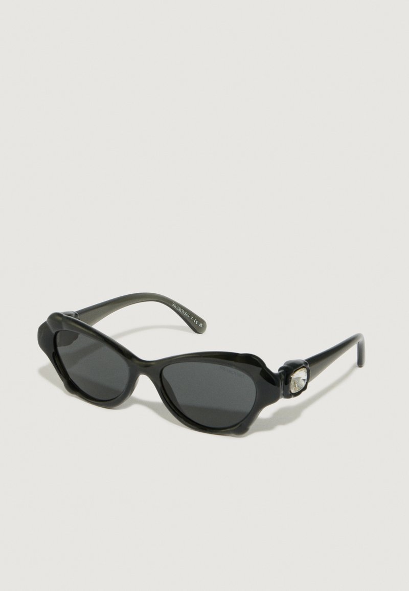 Gafas de sol negras con forma redondeada, con lentes oscuros y un acento floral texturizado en el lateral. Fabricadas en plástico brillante y elegante.