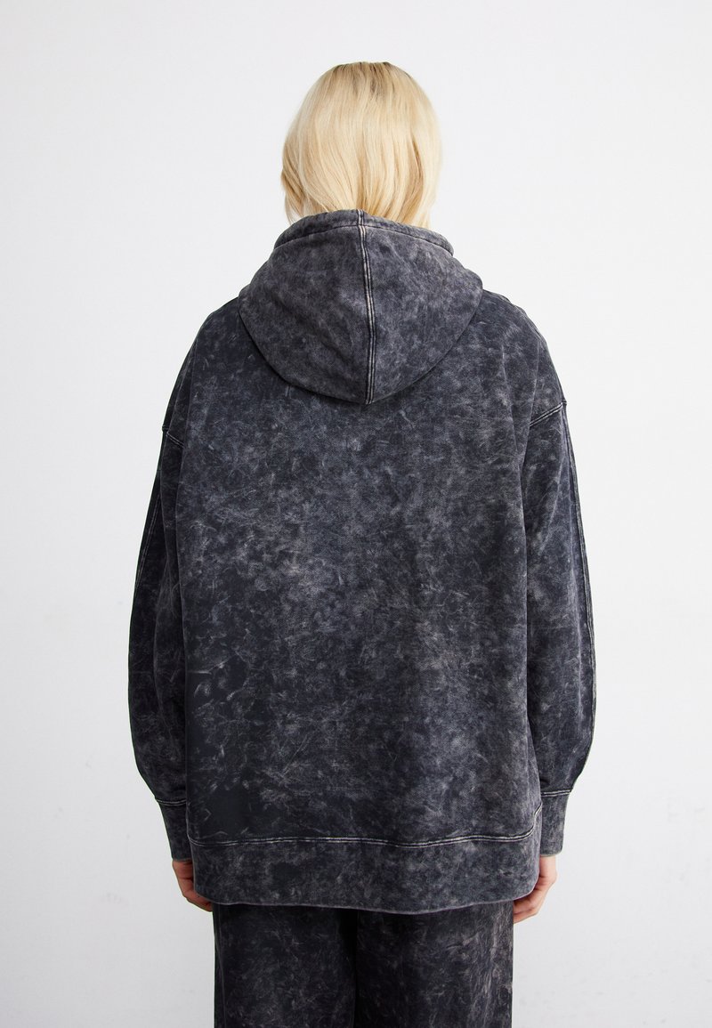 Sudadera gris de gran tamaño con un acabado desgastado y texturizado, cuenta con una gran capucha y costuras visibles. Diseño casual, sin detalles en la parte frontal.