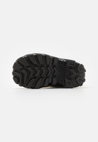 Suola di scarpa in gomma nera con un motivo di battistrada profondo, caratterizzata da scanalature e creste per un'ottima aderenza. Materiale durevole con una finitura testurizzata.