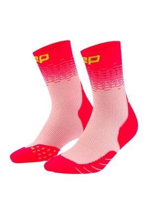 Pinke und rote Sportsocken in Crew-Länge mit gelben Buchstaben, strukturierten Fersen- und Zehenbereichen sowie einem Farbverlauf in Pixelmuster nahe dem oberen Rand.