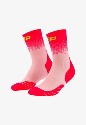 Pink and red athletic crew socks with yellow lettering, textured heel and toe areas, and gradient pixel pattern near the top.
