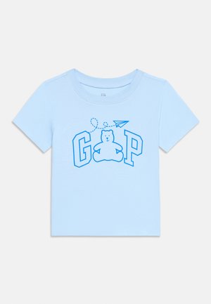 Svijetloplava majica za malu djecu s plavo obrubljenim medvjedićem između slova "G" i "P" te papirnatim avionom iznad.