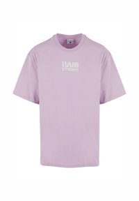 Lilac cotton t-shirt with short sleeves, round neckline, and a white "KANI STUDIOS" logo printed on the front. Smooth texture, loose fit.