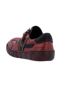 Chaussure en cuir rouge avec des accents noirs, bout arrondi, couture décorative, fermeture éclair sur le côté et semelle à motifs. Présente une texture lisse et un design décontracté.