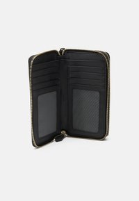 Svart lærpung med gullglidelås, flere kortlommer og to gjennomsiktige ID-vinduer. Jevn tekstur og kompakt design.