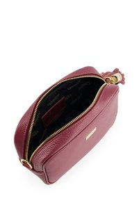 Burgundy leather bag with a smooth texture, gold zipper, and brand logo. Interior features a black fabric lining with repeated logo pattern.