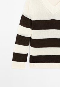 Maglione a righe caratterizzato da strisce alternate di crema e marrone scuro, design a V, maniche lunghe e una texture lavorata a maglia.