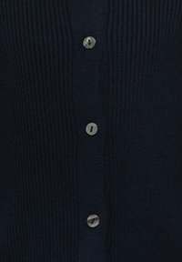 Temno modra pletena jopica z navpičnim rebrastim vzorcem, petimi sivimi gumbi in mehko teksturo. Preprost in funkcionalen dizajn.