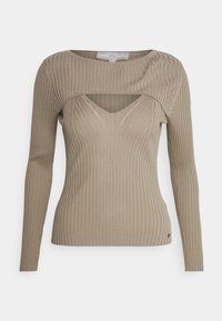 Haut à manches longues en maille côtelée beige avec une découpe sur le haut de la poitrine et un col en V en dessous.