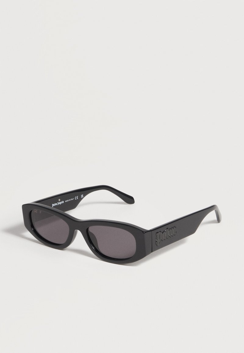 Lunettes de soleil rectangulaires noires avec verres foncés et branches épaisses, marquage "Palm Angels" visible à l'intérieur et sur le côté des montures.