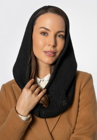 Accessorio nero a coste con collo a scialle in tessuto di maglia, caratterizzato da un bottone decorativo, abbinato a un cappotto color tan e una camicia bianca con colletto.