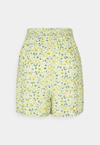 Shorts jaune clair avec ceinture élastique, recouverts d'un petit motif floral jaune et vert sur fond blanc.