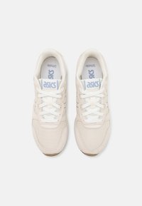 Helle beige Sneakers mit einem Mesh-Obermaterial, weißen Schnürsenkeln und dem Asics-Logo auf der Zunge. Gummisohle mit glatter Textur und detaillierter Naht.