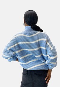 Blau-weiß gestreifter Strickpullover mit hohem Kragen, lockerer Passform und übergroßen Ärmeln. Strukturiertes Garn und umgeschlagene Bündchen sind bemerkenswerte Details.