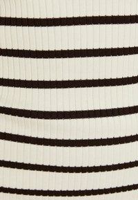 Gros plan sur un tissu côtelé avec des rayures horizontales noires uniformément espacées sur un fond crème.