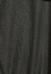 Μαύρη κάλτσα λαιμού με σκουρό πράσινο σχέδιο, απλωμένη σε λευκή επιφάνεια, που δείχνει την υφή του υφάσματος και τις ρολάριστες άκρες.