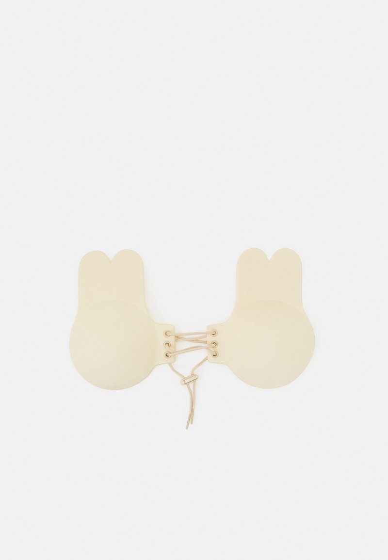 Soutien-gorge beige, doux, avec des bonnets arrondis et des formes d'oreilles de lapin. Présente un détail lacé au centre. Texturé lisse, design minimaliste.