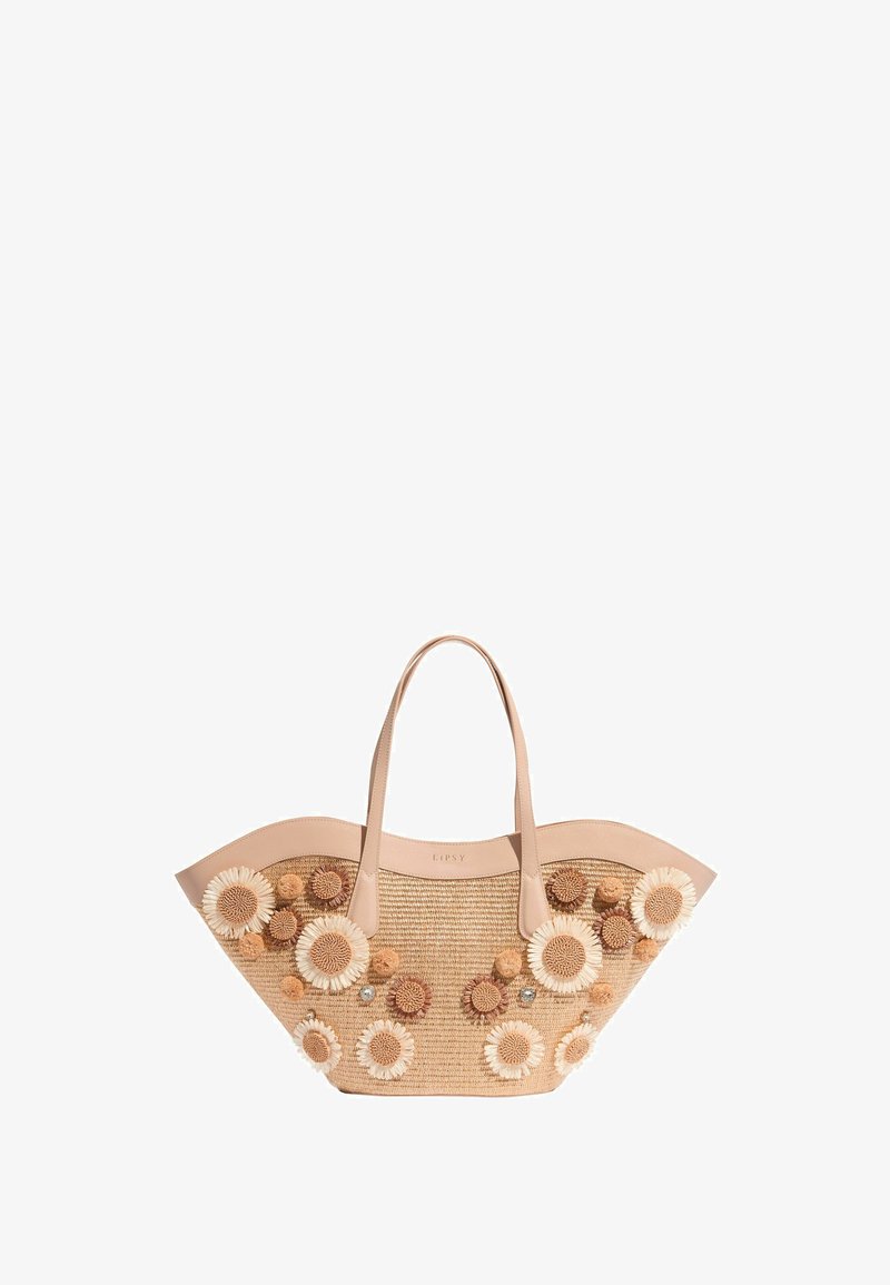 Sac cabas en paille avec ouverture large, poignées en cuir beige, et appliqués floraux 3D en blanc et beige sur le devant et les côtés.