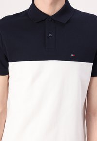 Marineblå og hvit polo skjorte i bomullsblanding, med to-farget design, tre-knapps placket og en liten logo på venstre bryst.