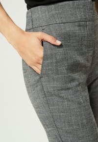 Grijze en zwarte geruite tailored broek met een zijzak, vervaardigd uit een textuurstof en een aansluitend ontwerp voor een gestructureerde uitstraling.