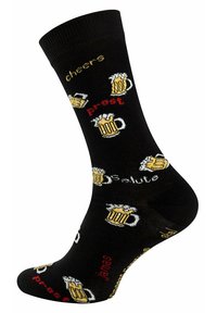Schwarze Socken mit wiederholten Grafiken von Bierkrügen und Texten wie "Cheers", "Prost" und "Salute" in Gelb und Rot. Aus Baumwollmaterial.