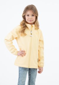 Geltona, užtrauktuku užsegama striukė su stovinčiu apykaklės, dviem šoninėmis kišenėmis ir elastingomis rankovėmis. Šiek tiek blizgi, su mažuoju siuvinėtų logotipu ant krūtinės.