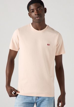 Lyse pink bomulds t-shirt med korte ærmer, rund hals og et lille rødt Levi's-logo på venstre bryst. Glat tekstur, klassisk pasform.
