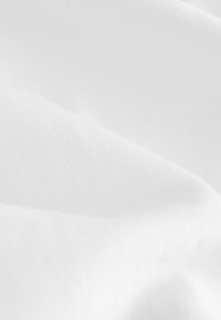 Weißer Stoff mit einer weichen, glatten Textur und einem gleichmäßigen Webmuster, gefaltet und in Schichten für Tiefe angeordnet.