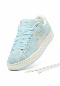 Világoskék velúr sneaker fehér kiegészítőkkel, kerek fűzőkkel és texturált gumitalppal. Az oldalon arany logó található.